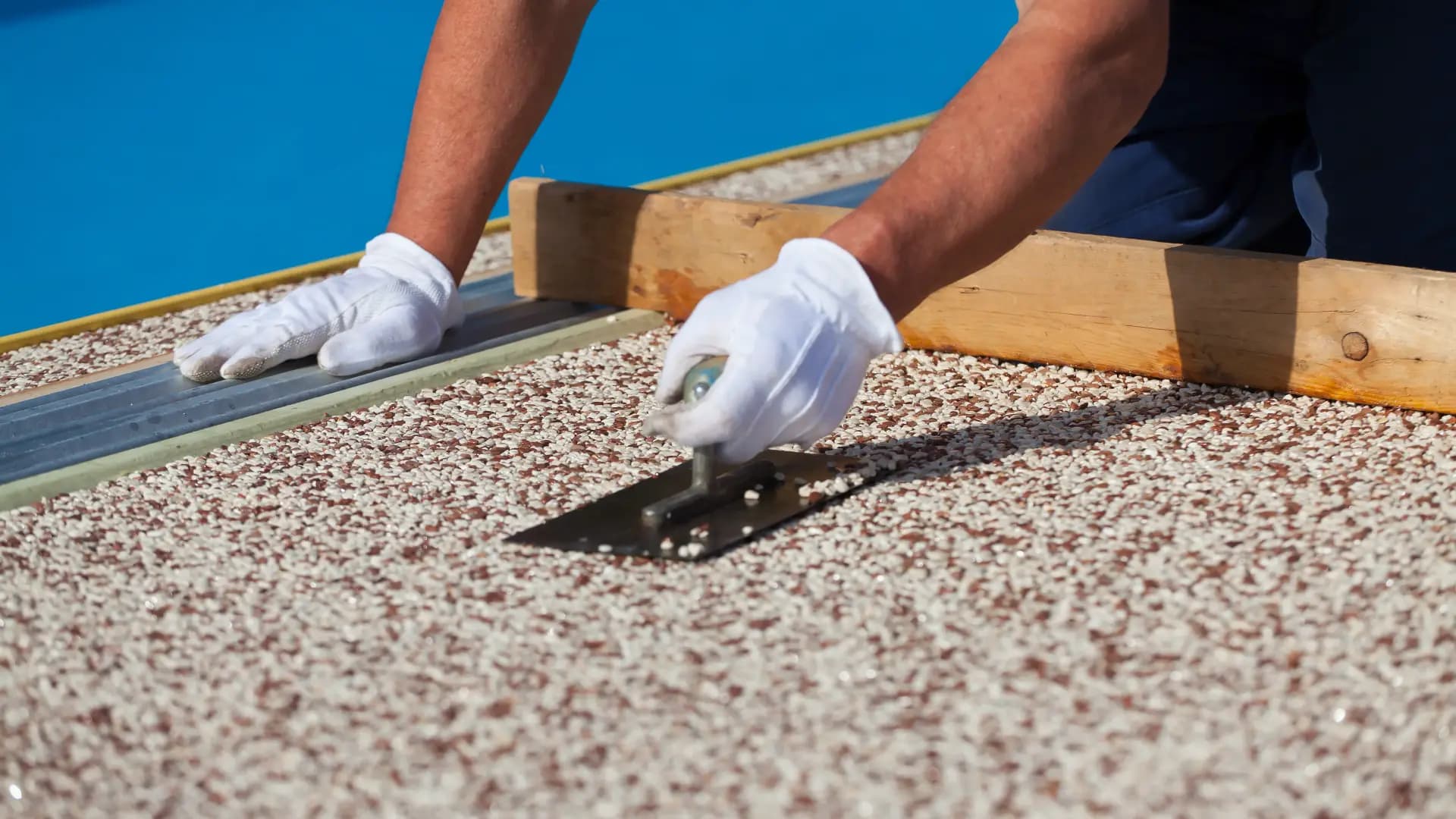 Marmorkiesel-Belag wird am Poolrand verlegt
